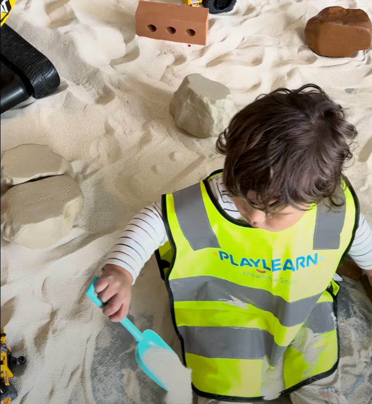 Child playing in sand at the sandbox for kids